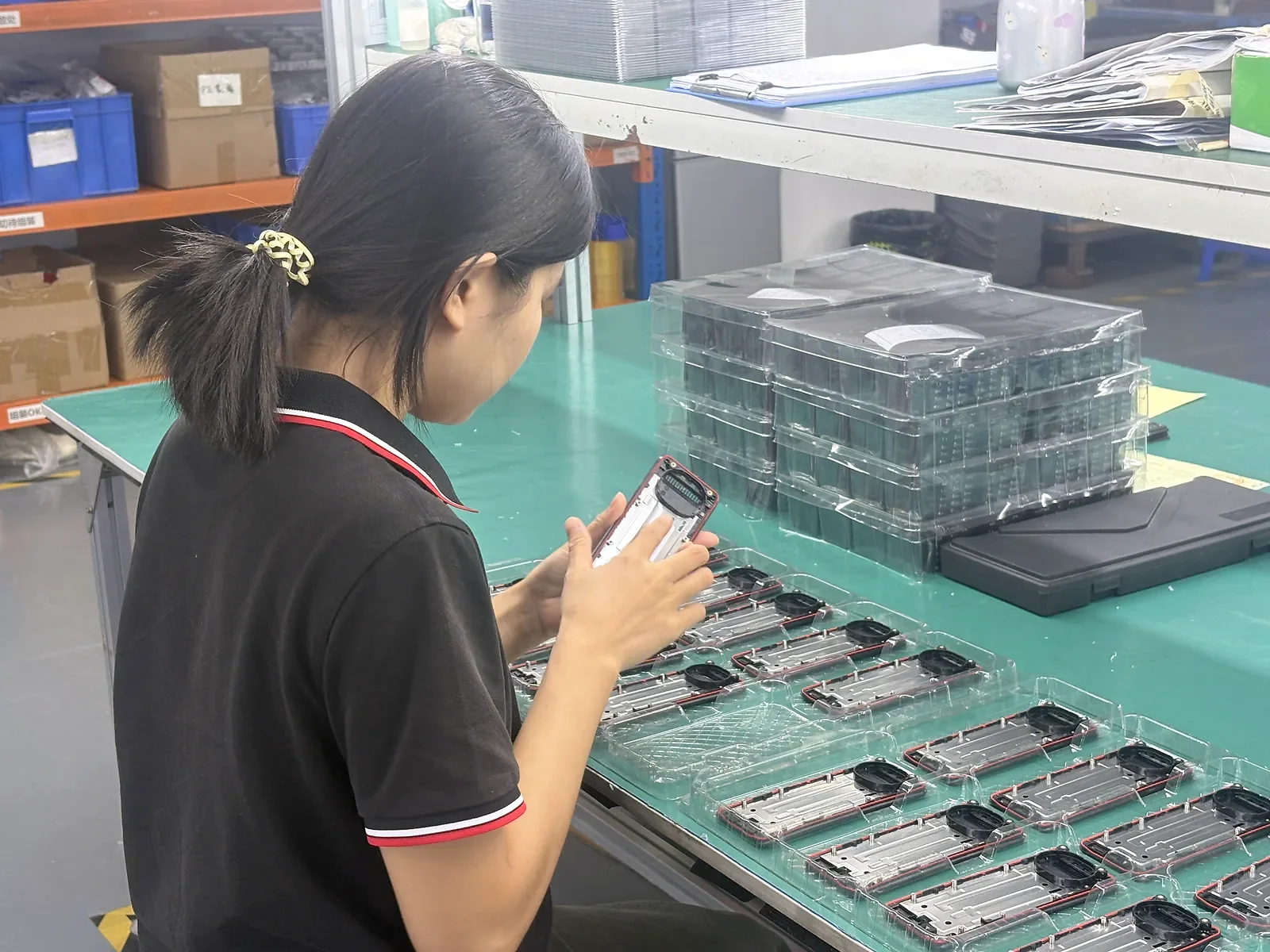 奥格工作人员在绿色工作台观察外壳结构件，旁边摆放待检部件